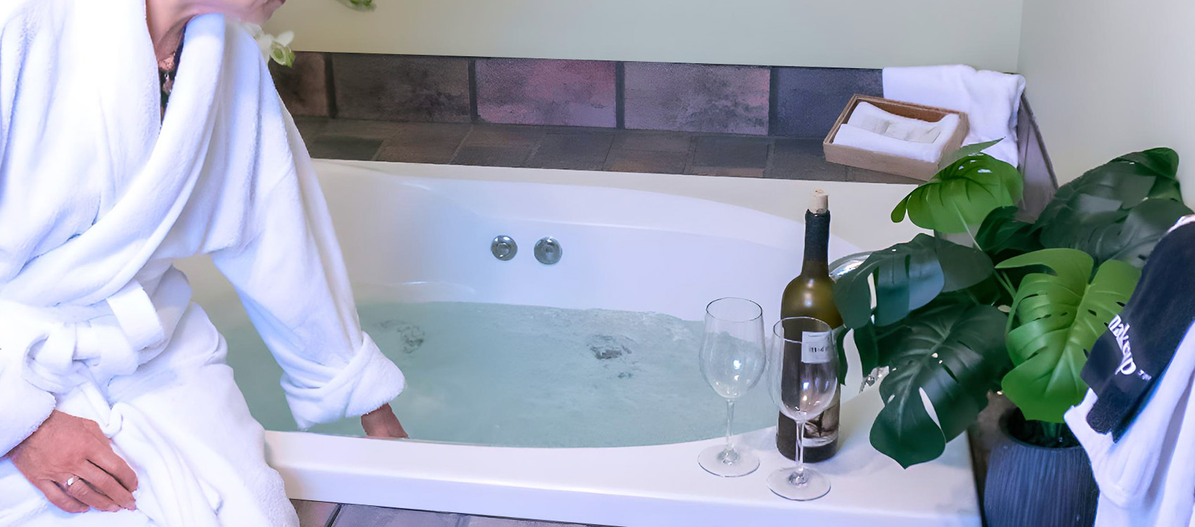 Person in robe touching water in tub
